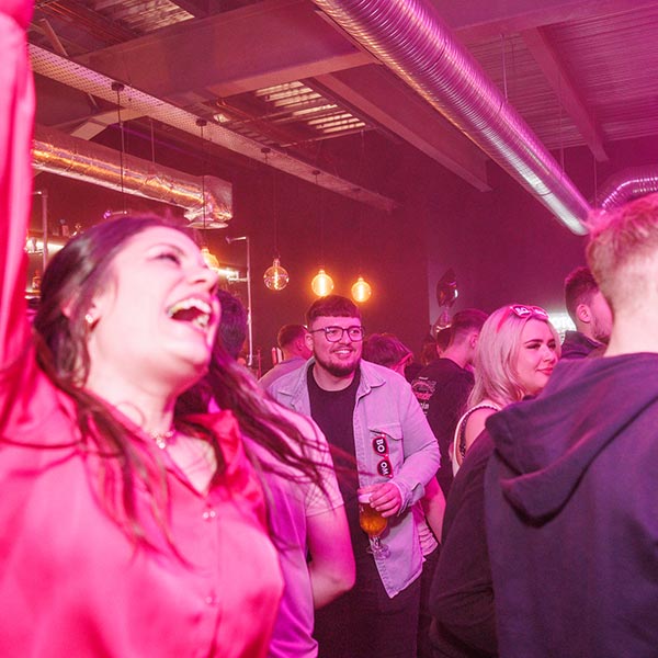 Woman in red satin blouse singing along to music with her arm in the air