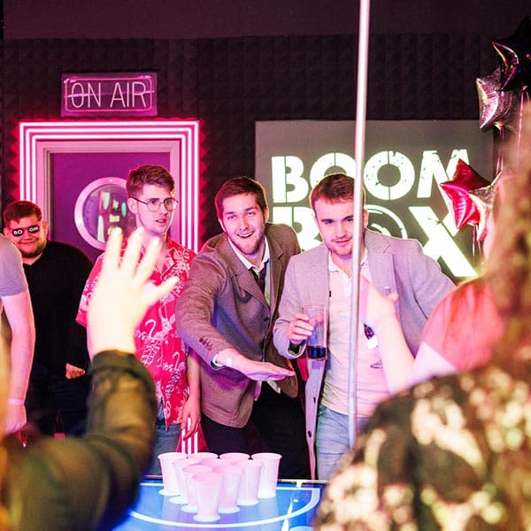 Three men in BOOM Battle Bar playing prosecco pong