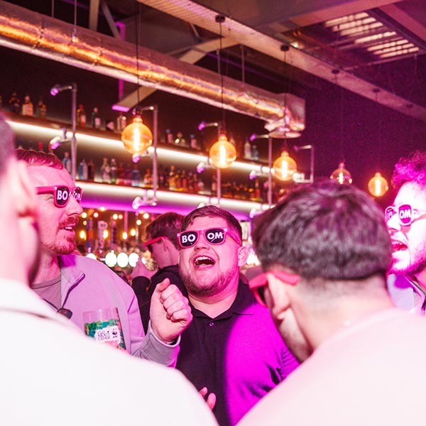 Men celebrating new years eve with BOOM fancy dress sunglasses on